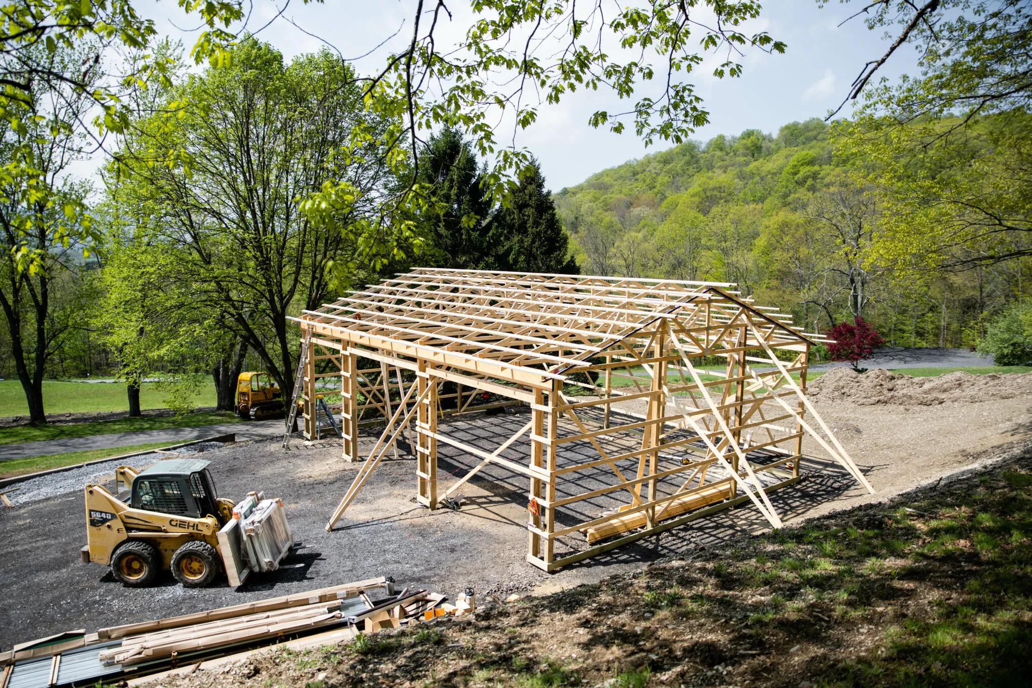 A post-frame building under construction with posts and roof trusses set
