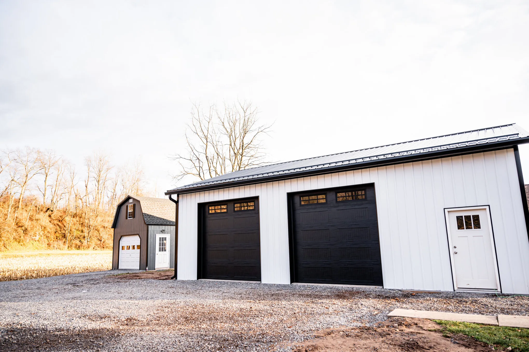 A white post-frame garage with black overhead doors