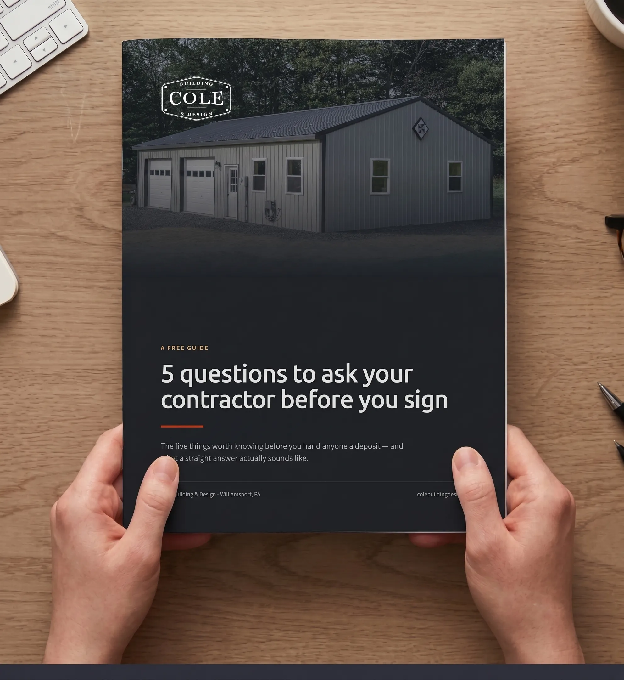 The printed guide held in two hands over a wooden desk, its cover reading '5 questions to ask your contractor before you sign'